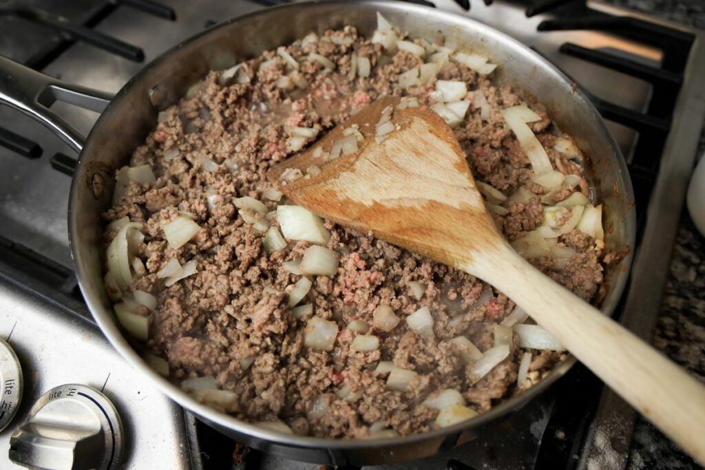 Ground beef in a sauté pan with onions and garlic. 