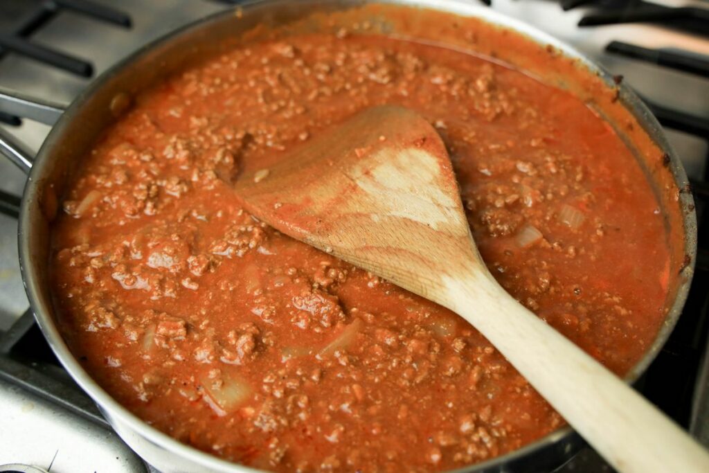 Tomato sauce, ground beef, and beef broth in a sauté pan.