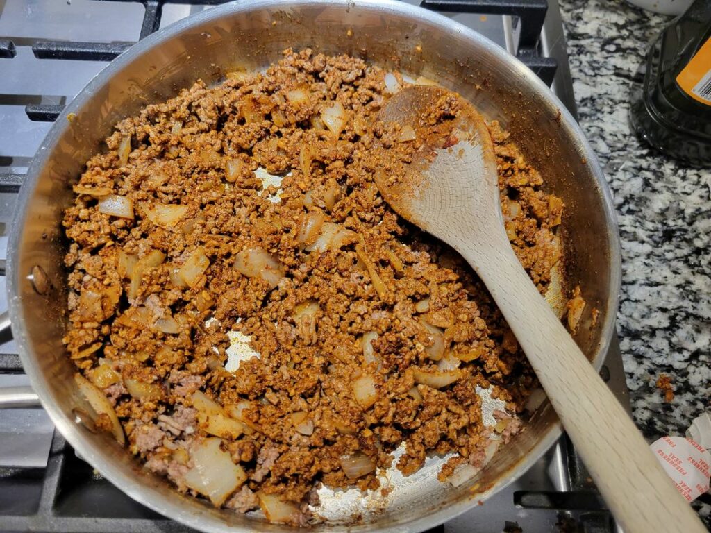 Ground beef in a pan with spices mixed in well.