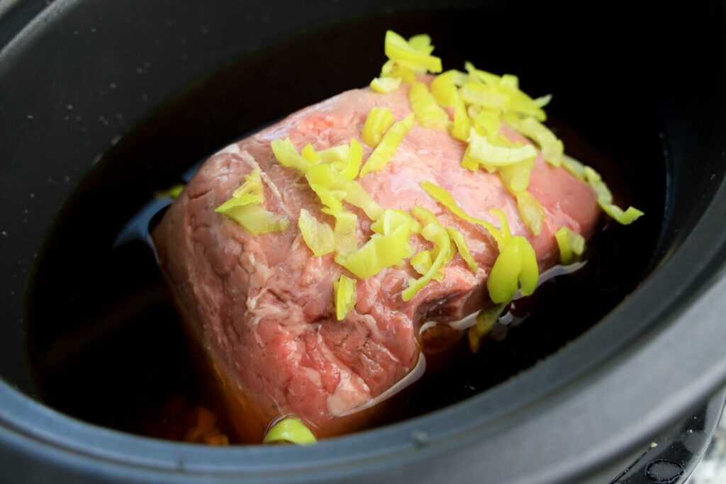 Beef roast in beef broth and pepperoncini juice in a slow cooker.