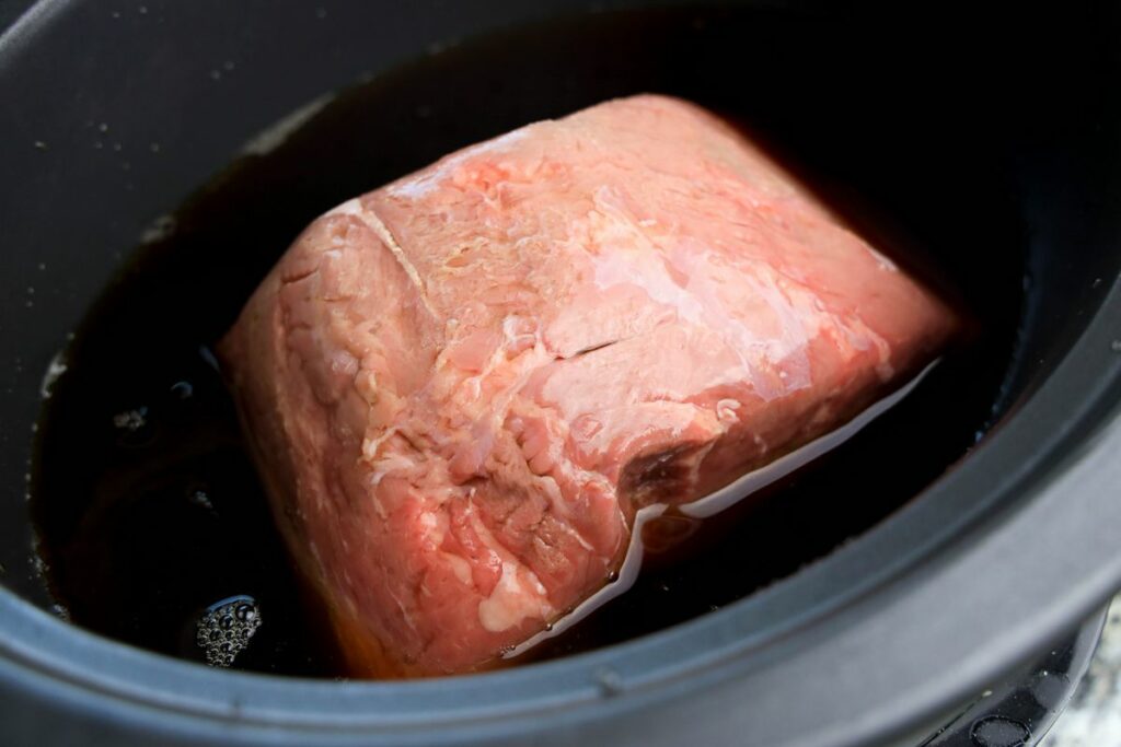 Beef roast in beef broth and pepperoncini juice in a slow cooker.