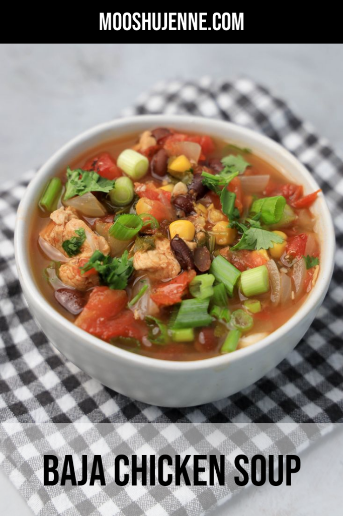 Baja Chicken Soup in a white bowl on a gray plaid napkin on a faux concrete backdrop.