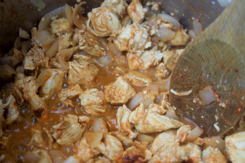 Chicken in a skillet with spices.