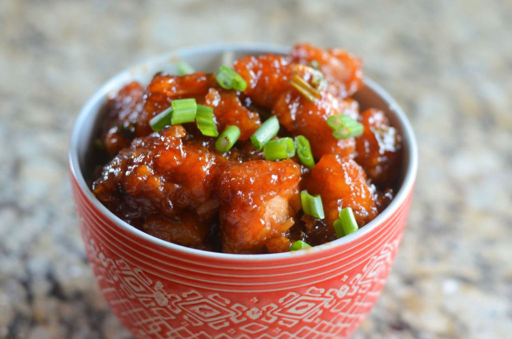 Sweet and Sour Chicken - Mooshu Jenne Topped with spring onions in a sweet and sour sauce topped over rice.