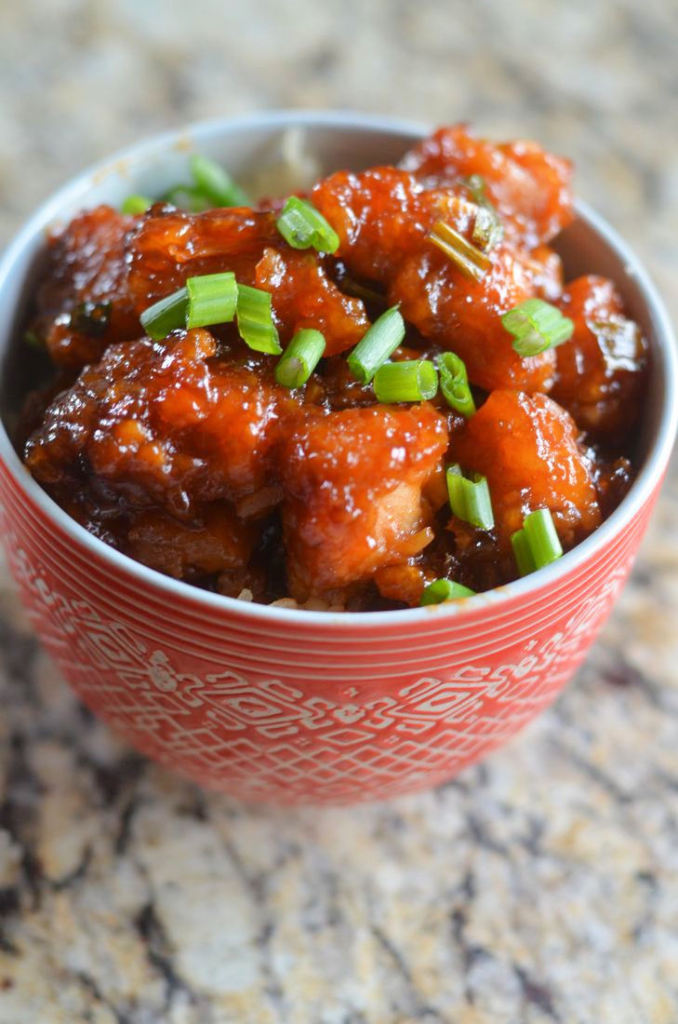 Sweet and Sour Chicken - Mooshu Jenne Topped with spring onions in a sweet and sour sauce topped over rice.