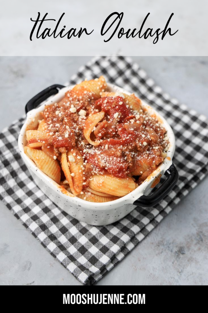 Italian Goulash with stewed tomatoes, onions, and bell pepper topped with parmesan cheese in a white bowl on a gray plaid napkin and concrete backdrop