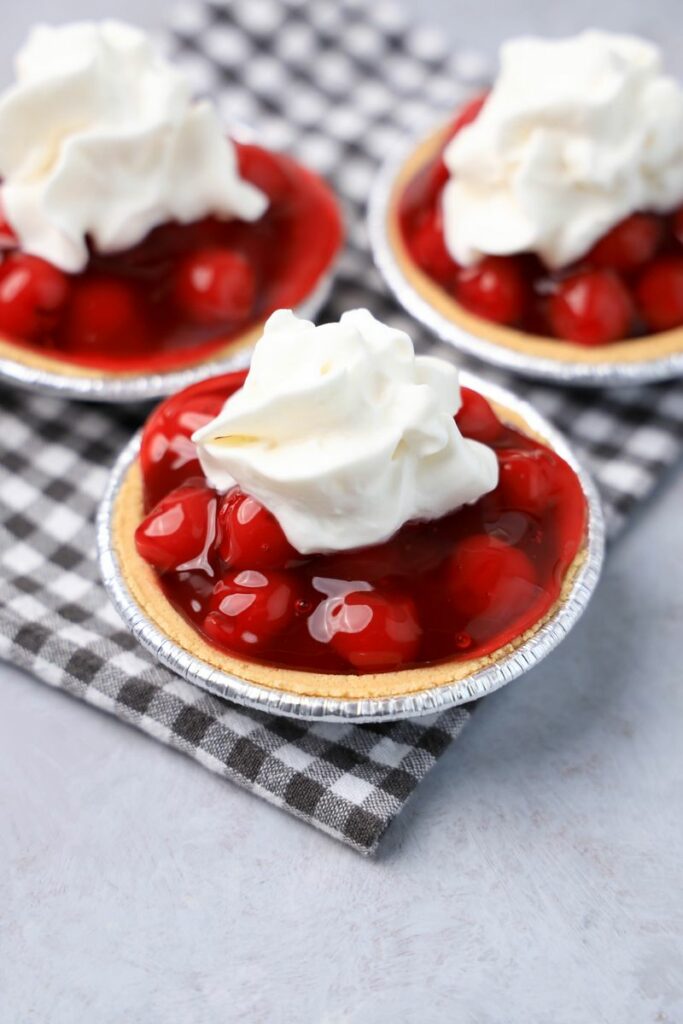 No Bake Mini Cherry Tarts on a gray plaid napkin on a faux concrete backdrop.