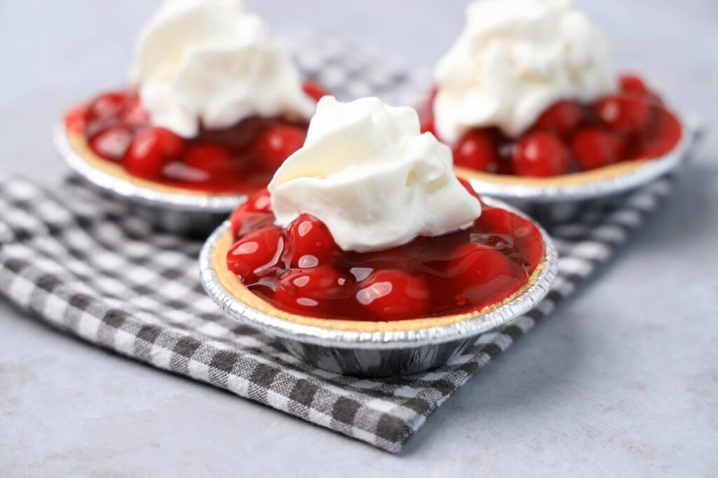 No Bake Mini Cherry Tarts on a gray plaid napkin on a faux concrete backdrop.