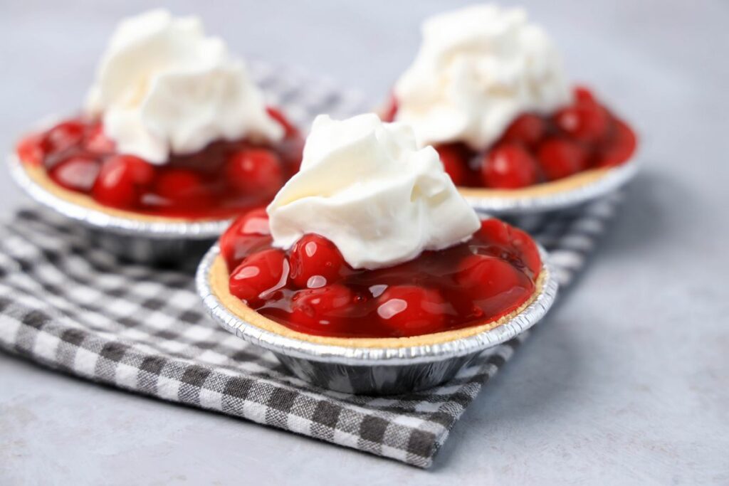 No Bake Mini Cherry Tarts on a gray plaid napkin on a faux concrete backdrop.