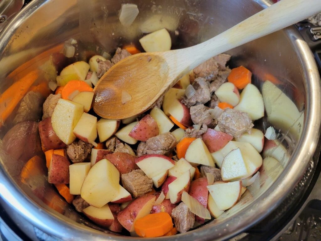Instant pot with beef, onion, carrots, celery, and potatoes.