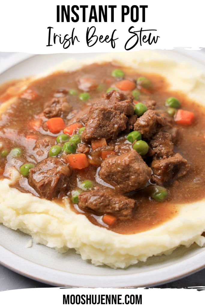 Instant Pot Irish Beef Stew plated on mashed potatoes on a stone plate with a gray plaid napkin.