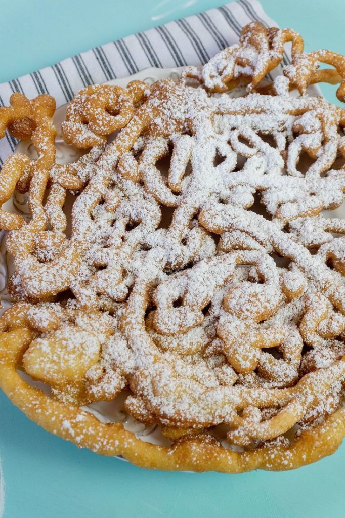 Funnel cake with powdered sugar on blue background