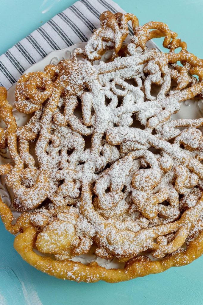 Funnel cake with powdered sugar on blue background