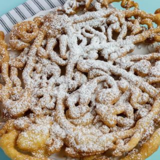 Funnel cake with powdered sugar on blue background