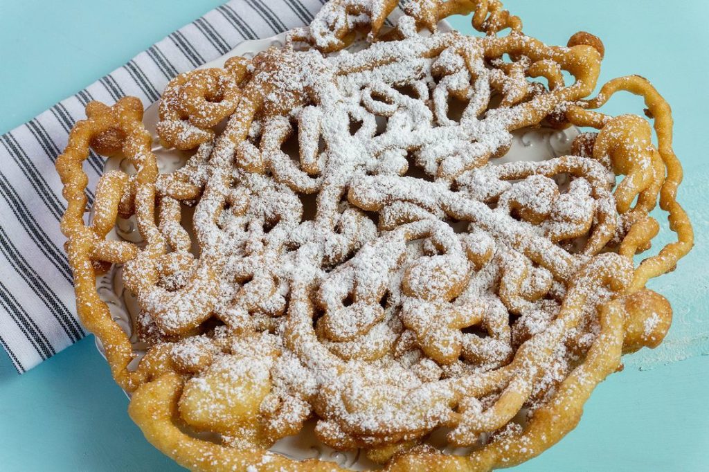 Funnel cake with powdered sugar on blue background