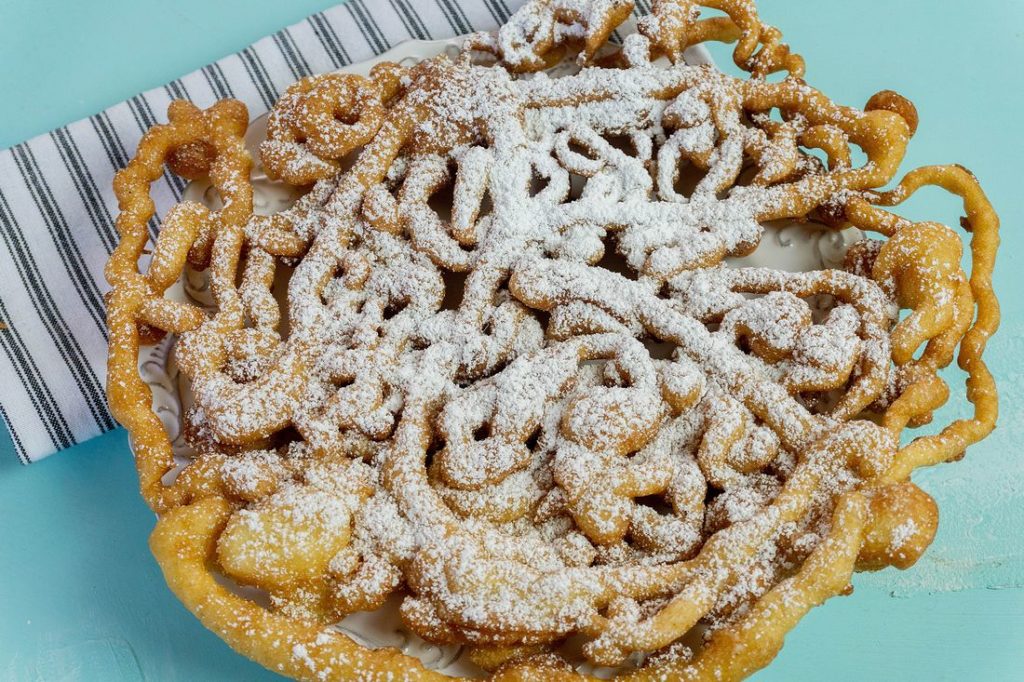 Funnel cake with powdered sugar on blue background