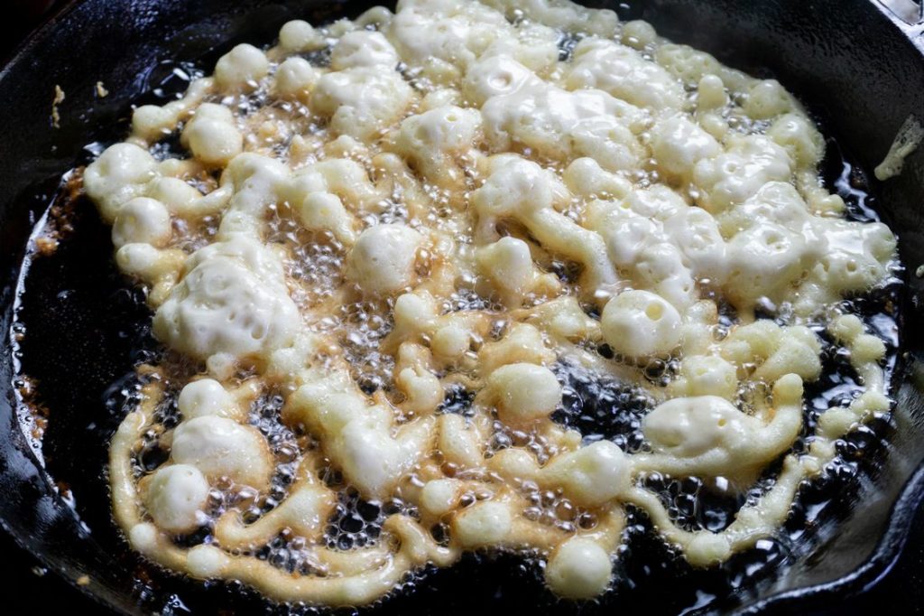 Funnel cake dough in oil in cast iron skillet