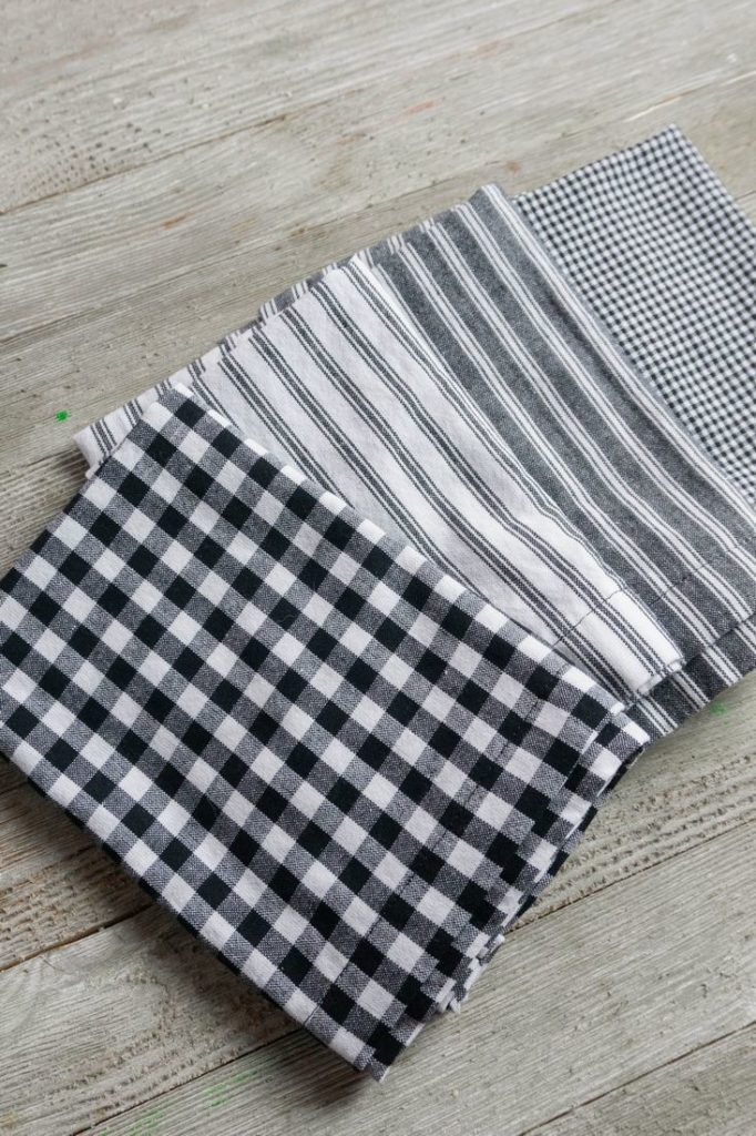 Napkins in gray, plaid, and stripes on a wood gray board