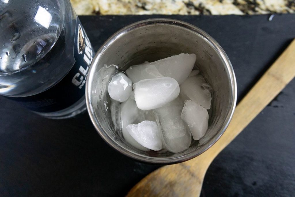 Ice in a shaker with moonshine bottle