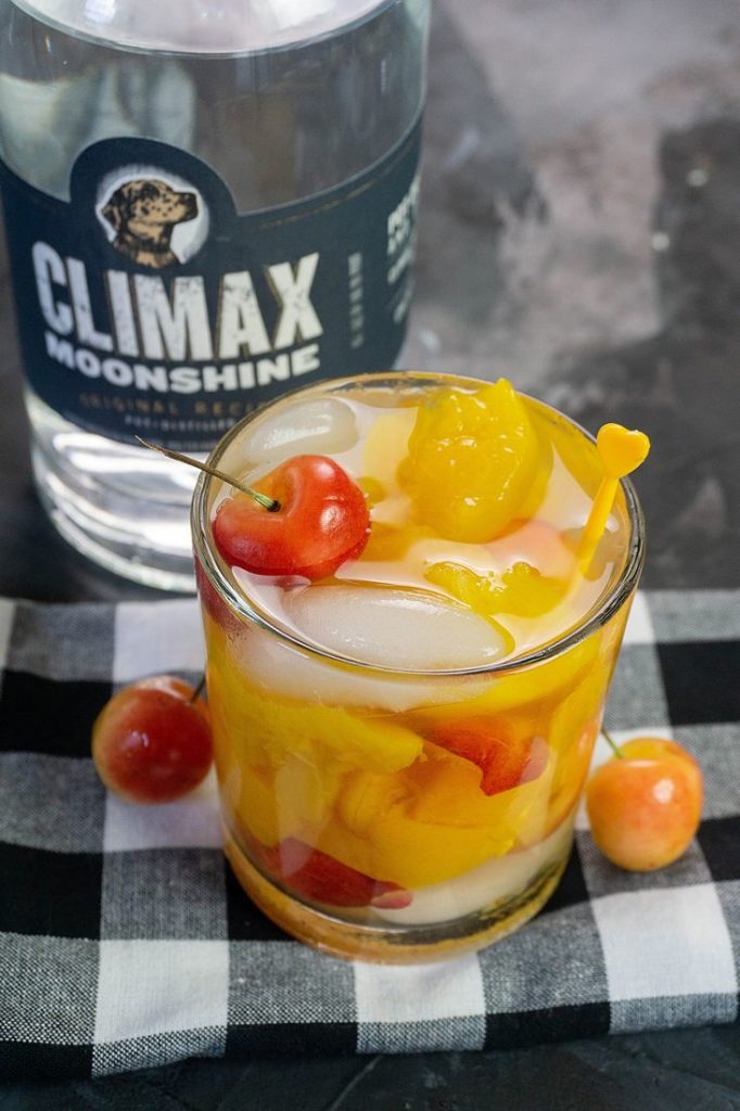 Rainier Cherry Peach Moonshine Cocktail with rainier cherries on a plaid napkin