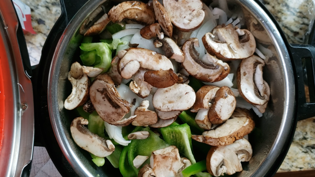 Meatballs, bell peppers, onions, and mushrooms in the instant pot on a steamer basket