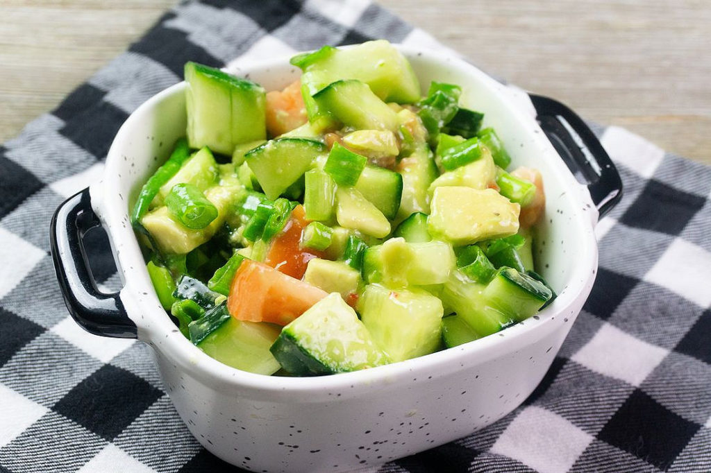 Avocado Cucumber Salad on grey backdrop with black and white plaid napkin