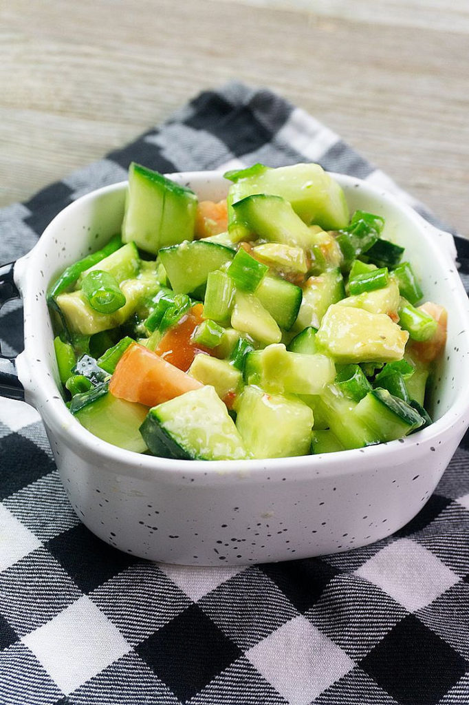 Avocado Cucumber Salad on grey backdrop with black and white plaid napkin