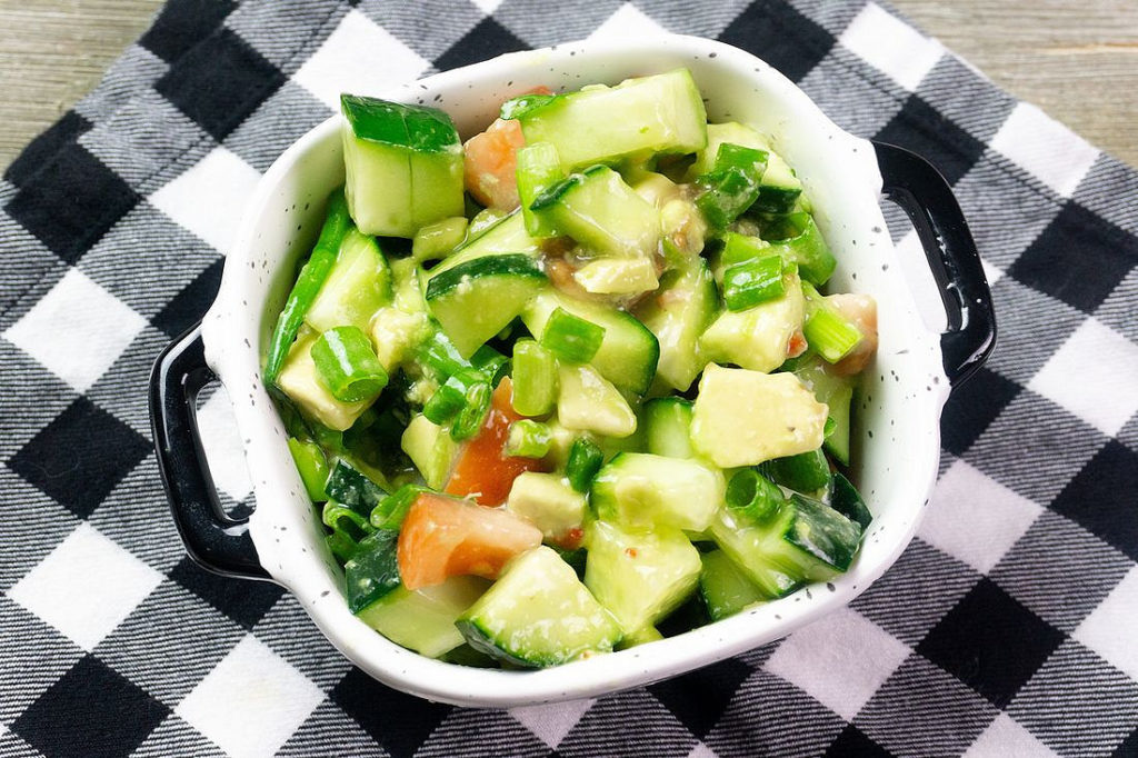 Avocado Cucumber Salad on grey backdrop with black and white plaid napkin