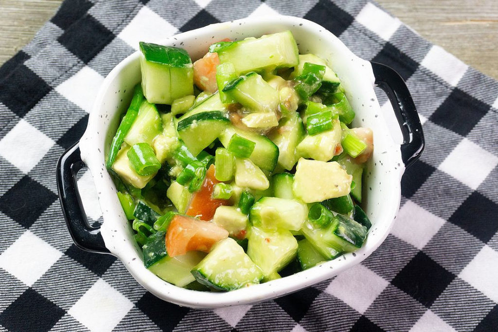 Avocado Cucumber Salad on grey backdrop with black and white plaid napkin