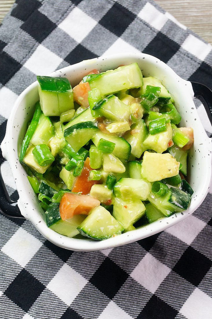 Avocado Cucumber Salad on grey backdrop with black and white plaid napkin