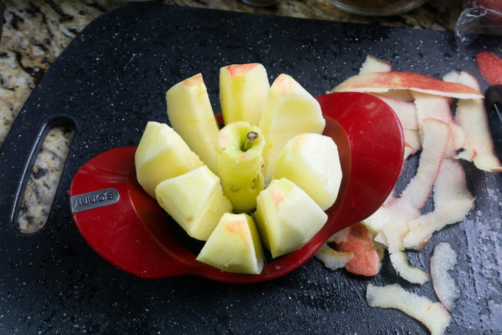 Apple corer on apple with black cutting board.