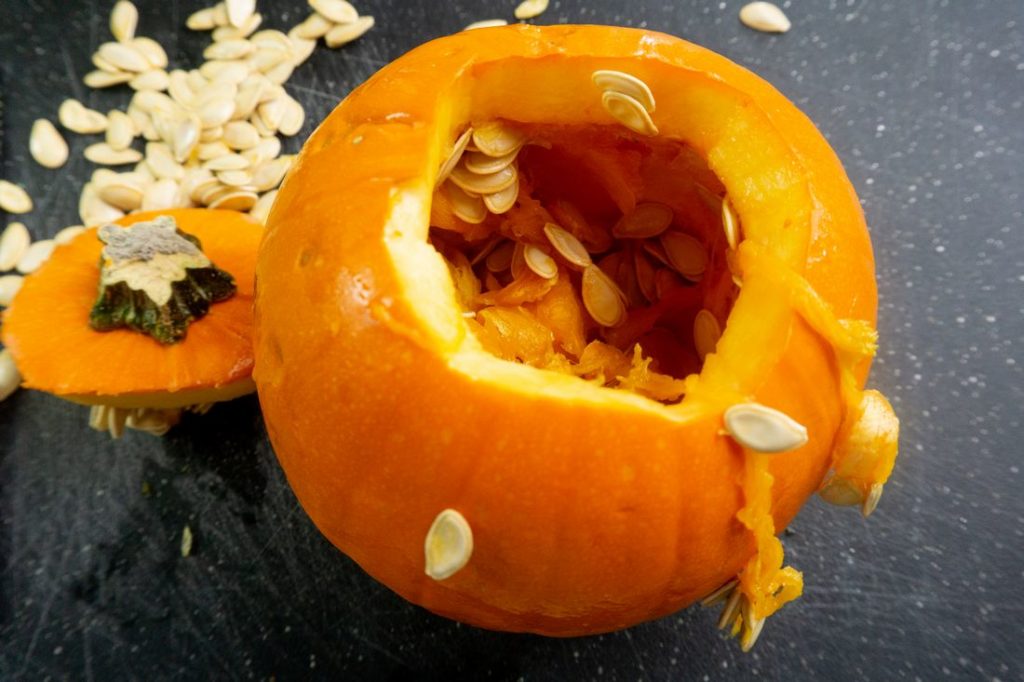 Pumpkin with top cut off on black cutting board