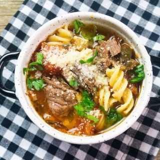Instant Pot Beef Parmesan Soup with plaid napkin on gray wood