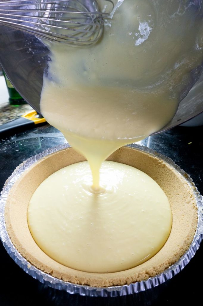 Key lime pie filling pouring into the pie crust