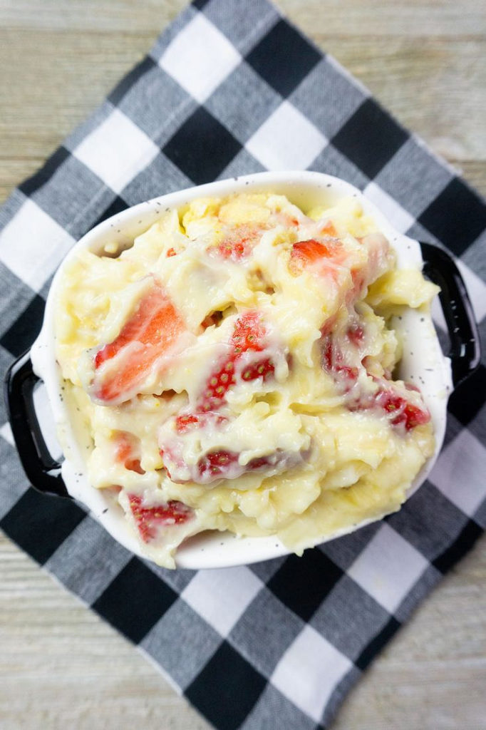 Strawberry Banana Delight in a black and white bowl on plaid napkin with gray wood background