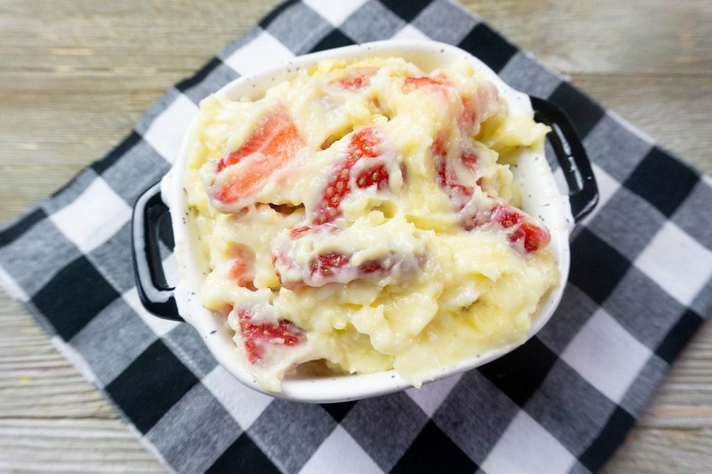 Strawberry Banana Delight in a black and white bowl on plaid napkin with gray wood background