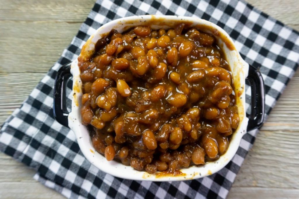 Instant Pot Baked Beans on a wood board in a black and white speckled bowl with black and white plaid napkin