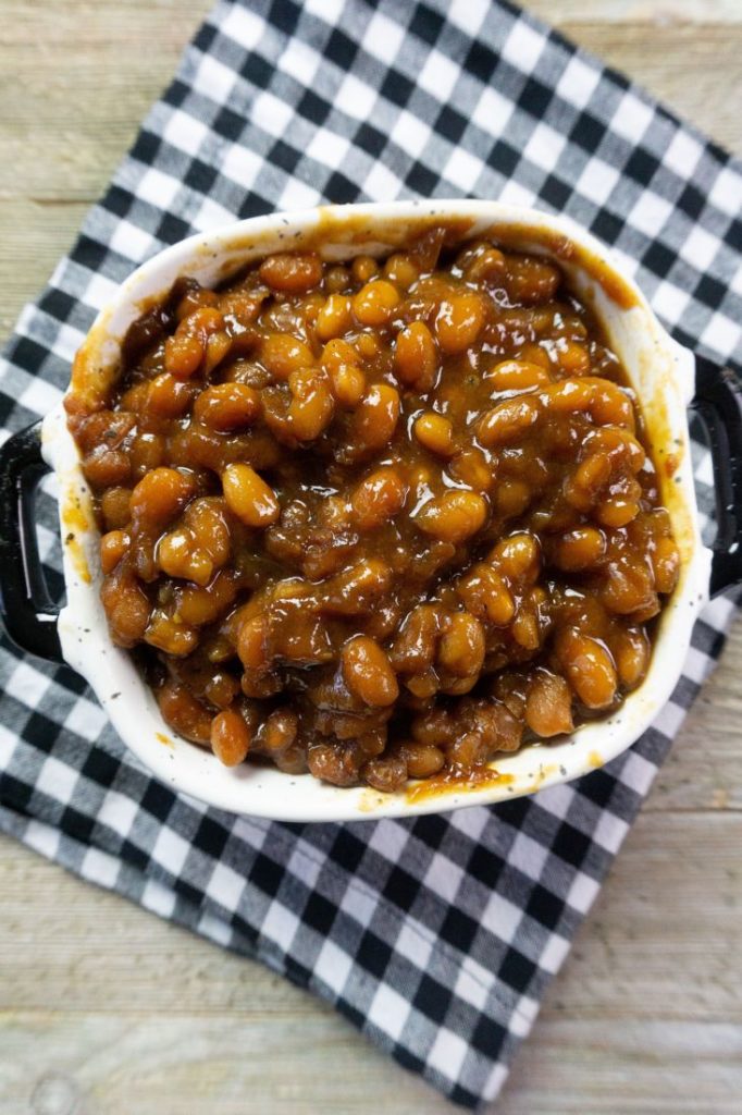 Instant Pot Baked Beans on a wood board in a black and white speckled bowl with black and white plaid napkin