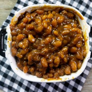 Instant Pot Baked Beans on a wood board in a black and white speckled bowl with black and white plaid napkin