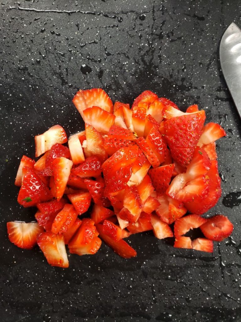 fresh cut strawberries on a black cutting board