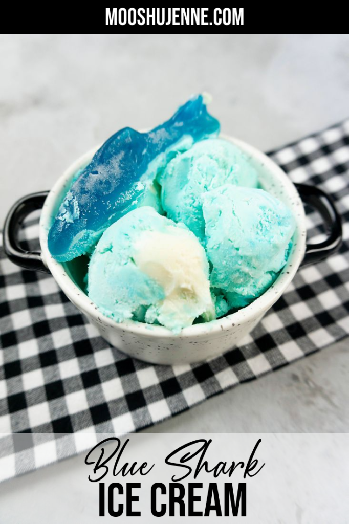 Blue Shark Ice Cream that resembles the ocean with white and blue in a white bowl with black and white plaid napkin