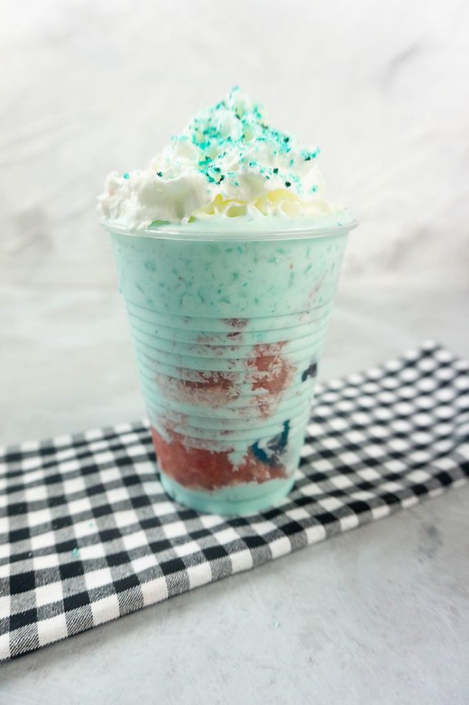 Shark Attack Frappuccino in a clear cup on a concrete background with plaid napkin