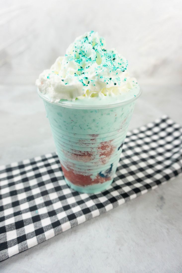 Shark Attack Frappuccino in a clear cup on a concrete background with plaid napkin