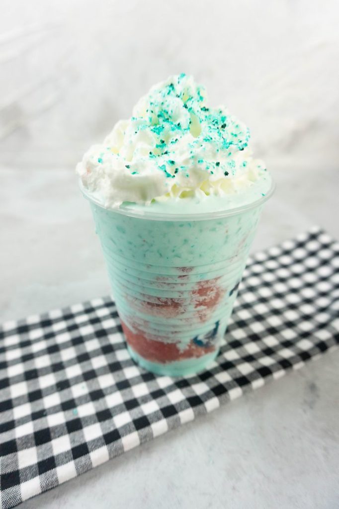 Shark Attack Frappuccino in a clear cup on a concrete background with plaid napkin