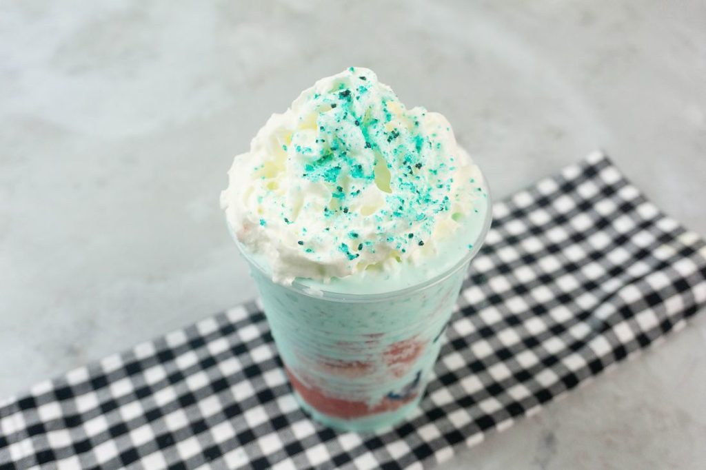 Shark Attack Frappuccino in a clear cup on a concrete background with plaid napkin