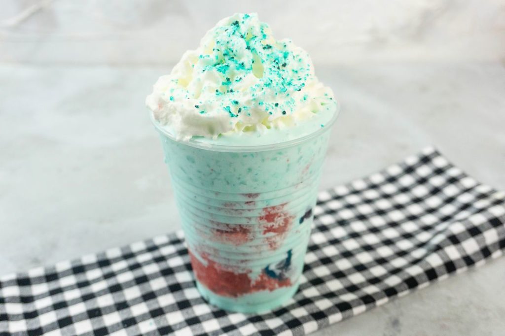 Shark Attack Frappuccino in a clear cup on a concrete background with plaid napkin