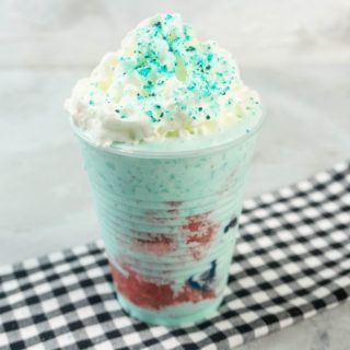 Shark Attack Frappuccino in a clear cup on a concrete background with plaid napkin