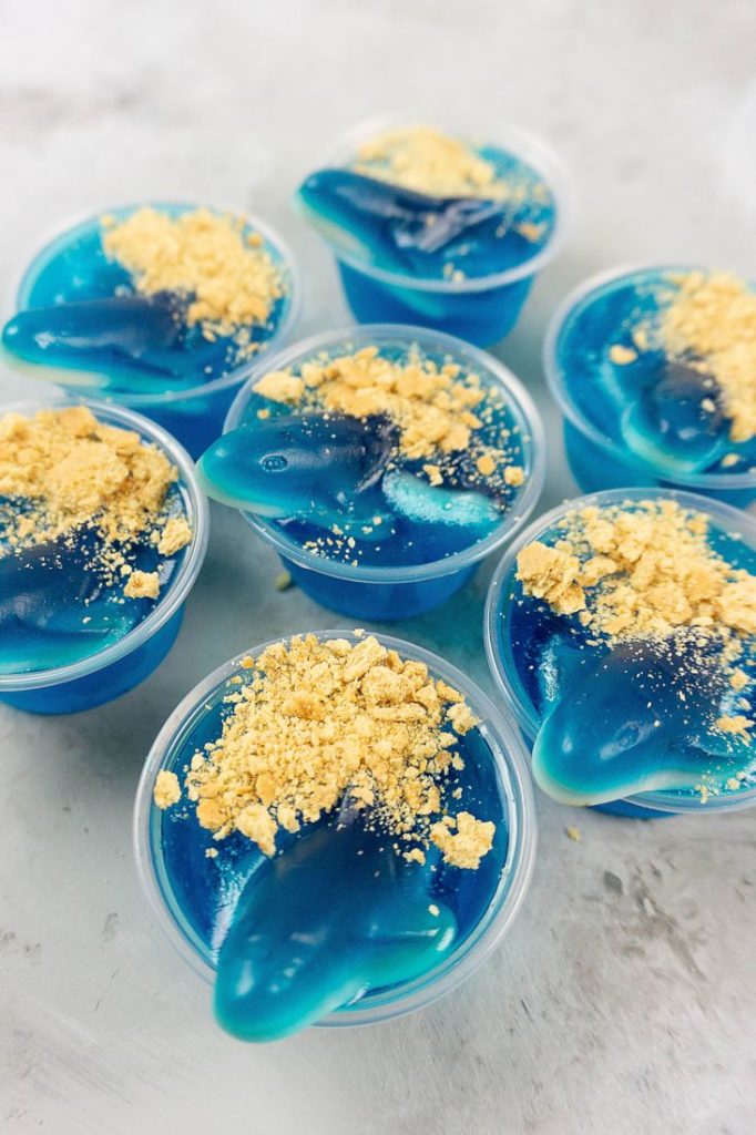 Shark Beach Jello Shots with gummy sharks, graham crackers as sand, and blue jello.