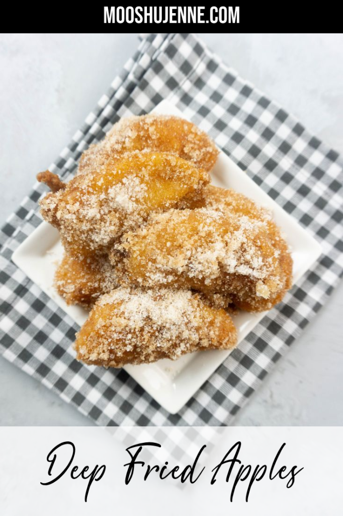 Deep fried apples on a white plate with cinnamon sugar on top on a plaid napkin and concrete backdrop