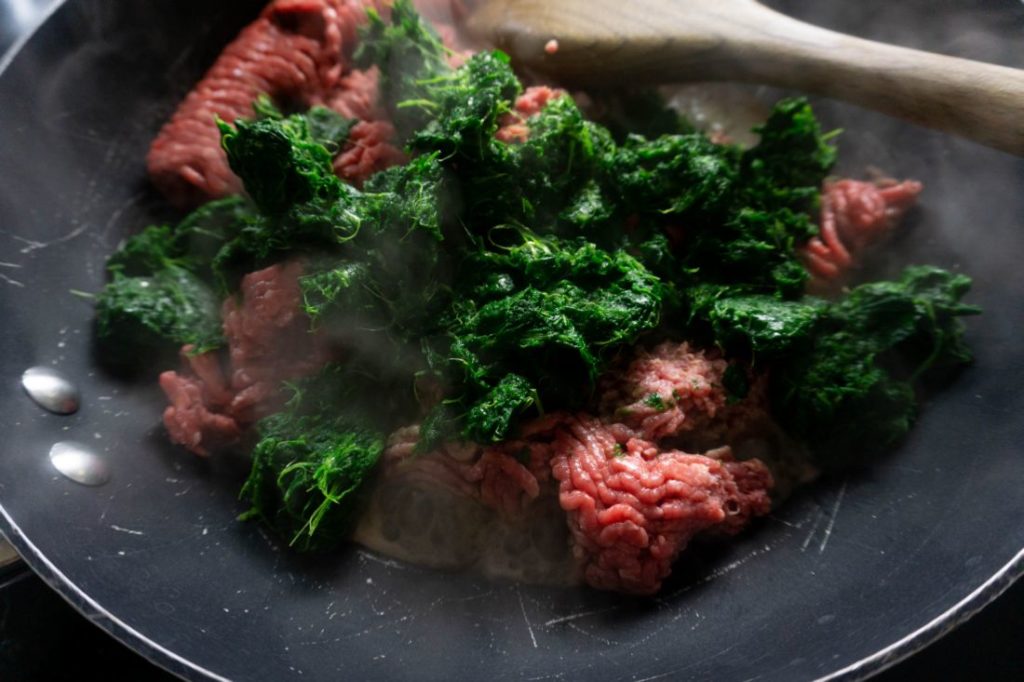 Ground beef and spinach in a sauté pan